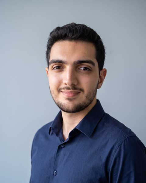 Retrato de Matheus Alvarenga, de camisa azul-marinho, com um sorriso leve.